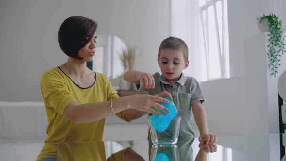 Mom and Son Sitting on the Floor Playing at the Table and Laughing Using an Elastic Toy