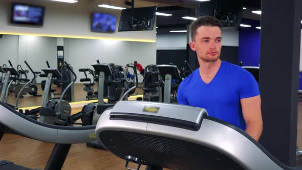 A Young Fit Man Walks on a Treadmill in a Gym - Closeup