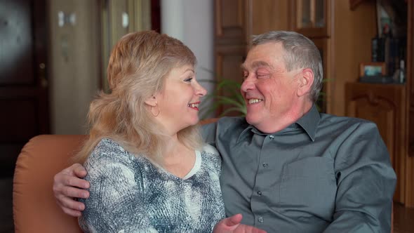 Cheerful old elderly 60s adult family couple hugging laughing bonding looking at camera