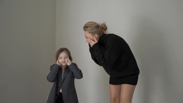 Active Mother in a Black Sweater and with Her Daughter in Jacket Fooling Around and Dancing at Home