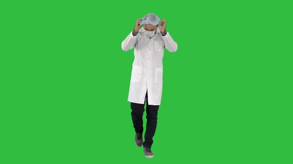 Walking handsome doctor wearing mask and cap on a Green