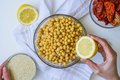 Cropped shot of woman, ingredients for hummus in bowl, sun-dried tomatoes, lemon, garlic, sesame - PhotoDune Item for Sale