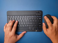 Top view someone hand typing wireless keyboard with holding mouse on blue background. - PhotoDune Item for Sale