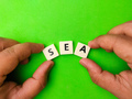 Top view hand holding toys letters with the word SEA on green background. - PhotoDune Item for Sale
