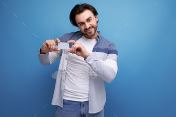 brutal brunette man in casual style with a money card to pay for purchases