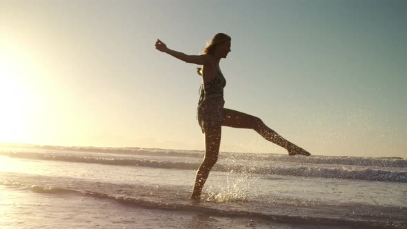 Woman with arms outstretched playing in water at beach