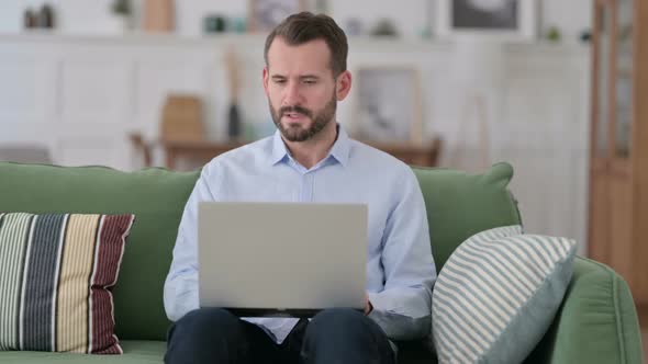 Young Man with Laptop Coughing on Sofa