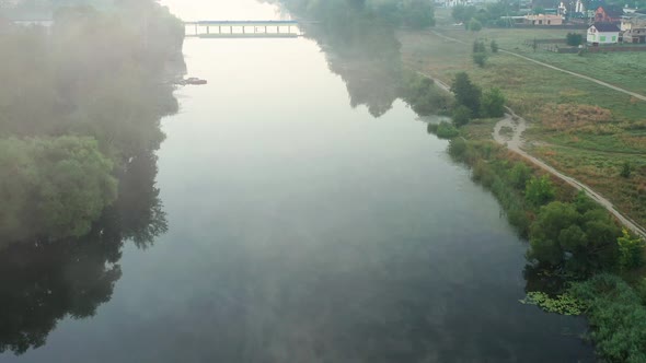 Beautiful morning, summer flight over the river. The bridge over the river in the fog, at dawn