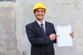 Happy Asian engineer man wearing hardhat pointing on clipboard with blank sheet for copy space  - PhotoDune Item for Sale