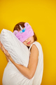 Nice teenage girl in white pyjamas with a violet sleeping mask embraces a pillow - PhotoDune Item for Sale