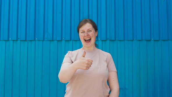 Paleskinned Positive Young Woman Shows Class Sign with Her Hand Thumbs Up