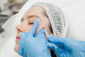 Close-up of the hands of a beautician injecting Botox into a woman's forehead. - PhotoDune Item for Sale
