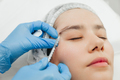 Close-up of the hands of a beautician injecting Botox into a woman's forehead. - PhotoDune Item for Sale