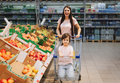 Family in the supermarket. young mother and her little daughter are smiling and buying food.  - PhotoDune Item for Sale