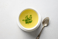 Chicken broth with greens in white bowl over white table. Copy space. - PhotoDune Item for Sale