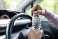 Asian woman driver holding bottle for drink water while driving a car.  - PhotoDune Item for Sale