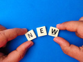 Top view hand holding toys letters with the word NEW on blue background. - PhotoDune Item for Sale