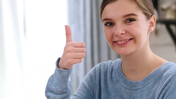 Thumbs Up By Young Woman at Home Looking at Camera