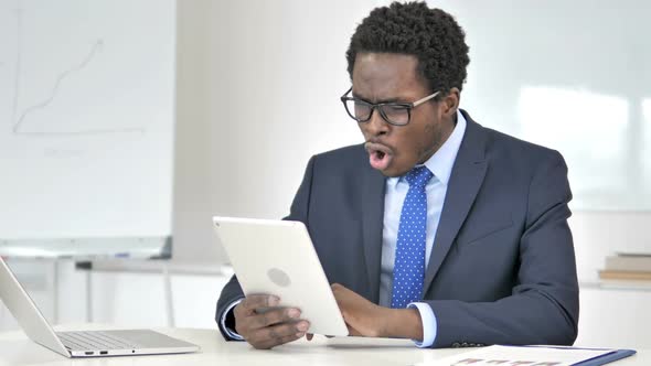 African Businessman Reacting to Financial Loss on Tablet