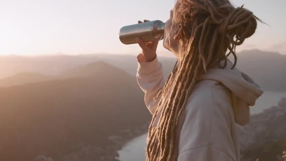 Dreadlocks travel woman drinking water from metal zero waste bottle