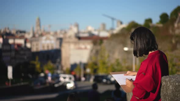 Woman Artist Street Painter with Pencil Draws City Sketch