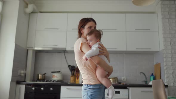 Mother Embrace Baby at Home in the Kitchen