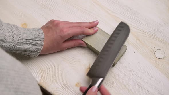 Close-up of a woman sharpening a kitchen knife on a table