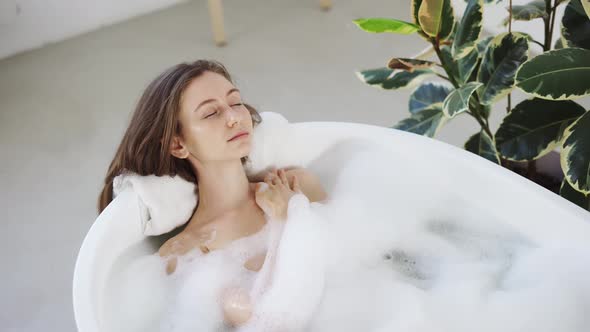 Sexy Girl Taking Bathtub with Bubbles and Foam in Slow Motion