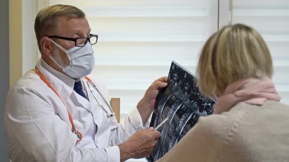 Senior Male Traumatologist Explaining X-rays To the Female Patient. Doctor and Patient in Medical