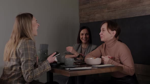 Cheerful Female Friends Have Breakfast in Asian Cafe