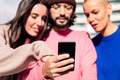 man holding phone sharing with two female friends - PhotoDune Item for Sale