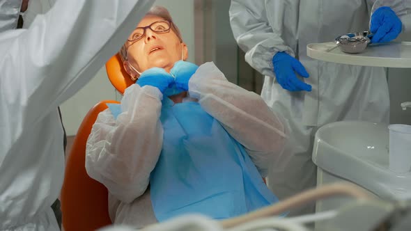 Dentist Technician in Coverall Lighting Lamp for Examining Patient