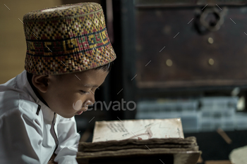 Smart school Asian boy reading an antique book at the Pedir Museum Aceh