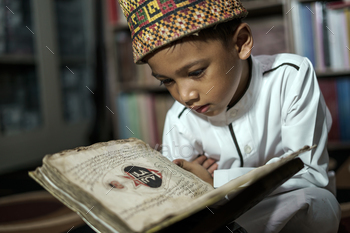 Smart school Asian boy reading an antique book at the Pedir Museum Aceh