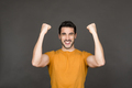 Joyful Caucasian young man celebrating in studio with arms raised, copy space - PhotoDune Item for Sale