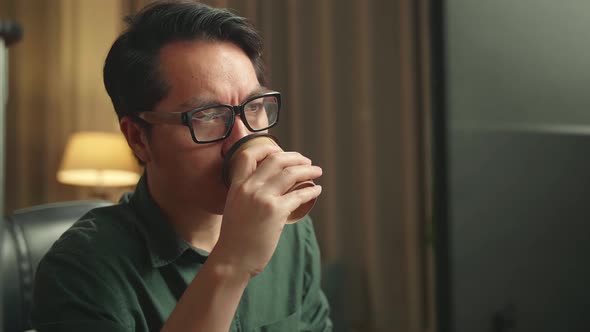 Asian Man Drinking Coffee While Works On Personal Computer And 3D Printer In Home Office