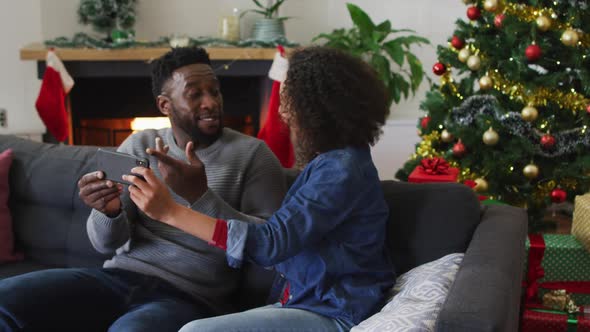 Smiling african american couple having video call and gesturing, christmas decorations in background