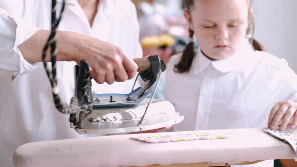 Grandma with Little Granddaughter Iron Clothes in the Factory