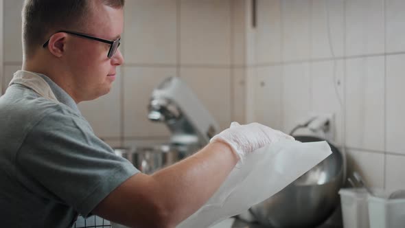 Caucasian man with down syndrome preparing a meal to take away in commercial kitchen. Shot with RED