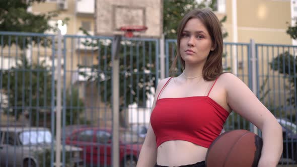 Portrait of Young Athletic Woman Teenager with Ball on Basketball Court Outdoors