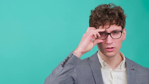 Curly Haired Handsome Young Man That is Putting on Eye Glasses and Smiling