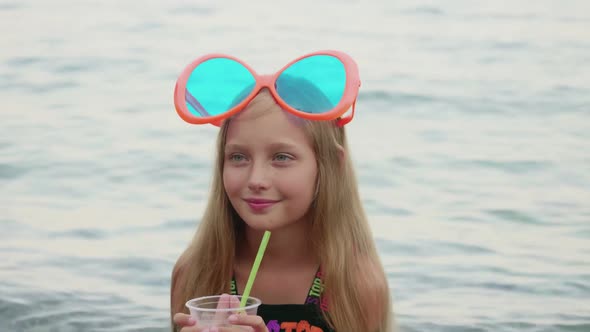 Adorable Happy Girl Drinking Cocktail From Plastic Cup Near Sea
