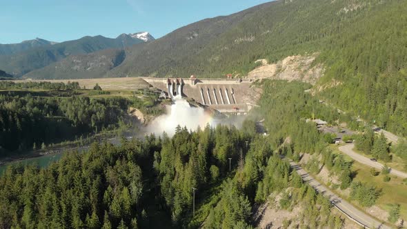 Aerial Shoot of Revelstoke Dam at noon, Surrounded by Mountrains and Pine Trees