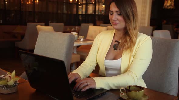 Business Woman in Business Clothes Typing on Mobile Computer Sitting at Table