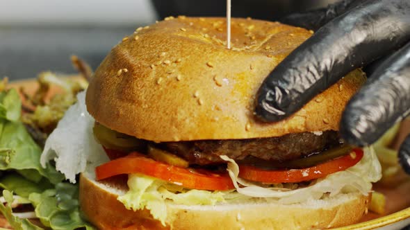 Large hamburger placed on a bun with vegetables in slow motion