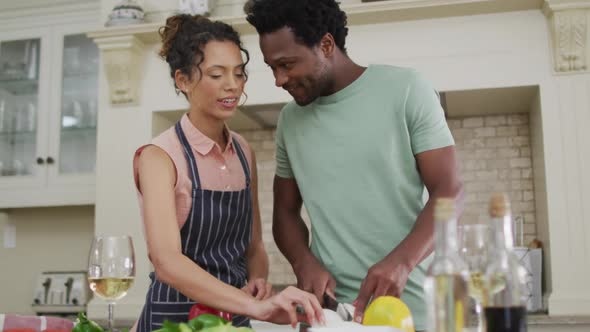 Happy biracial couple cooking together, cutting vegetables