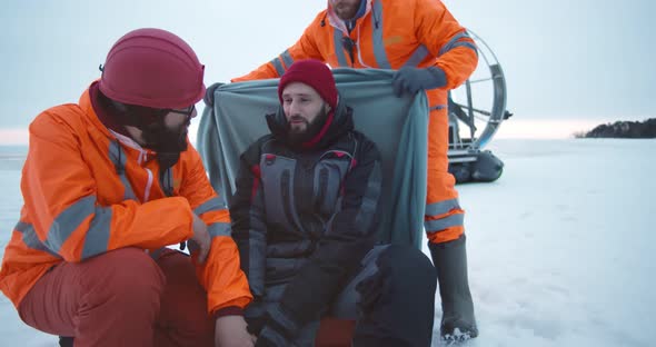 Coast Guards Rescuing Young Man with Injured Leg on Frozen Lake