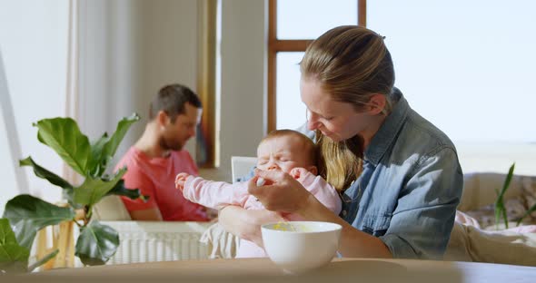 Baby boy crying while mother feeding him food 