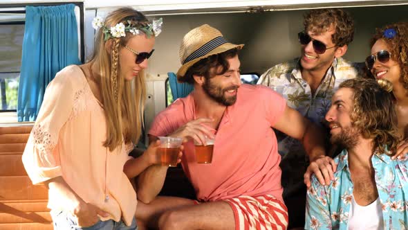 Group of friends drinking some beer and sitting on the van