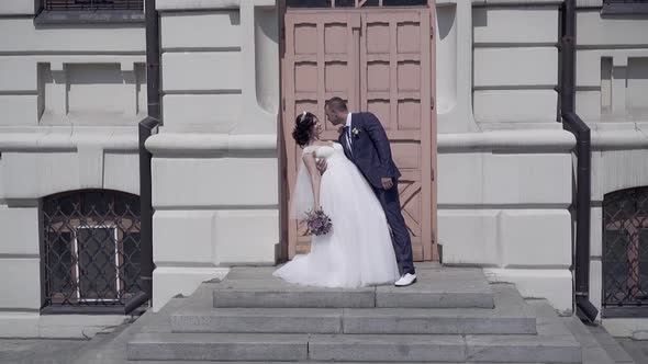 Slow Motion Handsome Groom Holds Bride Against Brown Door